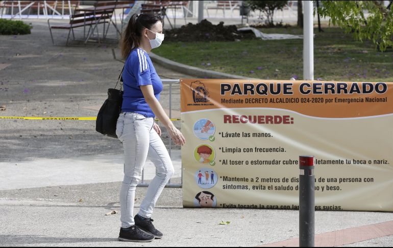 Una mujer camina al frente de un letrero que dice 