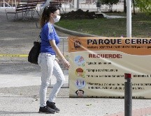 Una mujer camina al frente de un letrero que dice 