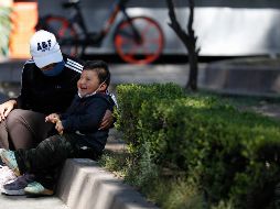 Una mujer cubierta con un cubrebocas platica con su hijo en un parque. AP/R. Blackwell