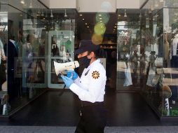 Una policía advierte a personas en la calle ayer en Monterrey, Nuevo León, que se queden en sus casas para evitar la expansión del COVID-19. AFP/ARCHIVO