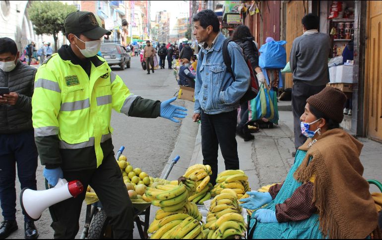 Un policía informa en un mercado sobre las restricciones decretadas por las autoridades bolivianas, este jueves en La Paz. EFE/L. Reglero