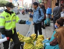 Un policía informa en un mercado sobre las restricciones decretadas por las autoridades bolivianas, este jueves en La Paz. EFE/L. Reglero