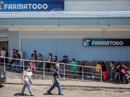 Decenas de personas hacen fila para abastecerse de medicamentos y productos de higiene personal en una farmacia de Caracas. EFE/R. Peña