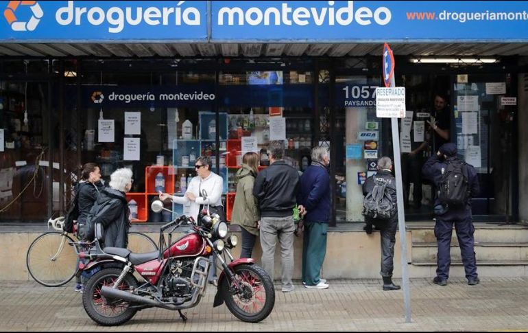 Personas hacen fila en una droguería para adquirir productos como alcohol líquido y en gel en Montevideo. EFE/R. Martínez