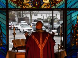 Un sacerdote oficia misa desde un templo católico en Johnston, en el estado de Rhode Island  mientras fieles escuchan la ceremonia desde sus carros, como parte de las medidas de distanciamiento social. AP/D. Goldman