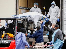 Personas en atuendo protector contra el COVID-19 trasladan un cuerpo envuelto en plástico en un hospital en Brooklyn, en la ciudad de Nueva York. AP/J. Minchillo