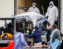 Personas en atuendo protector contra el COVID-19 trasladan un cuerpo envuelto en plástico en un hospital en Brooklyn, en la ciudad de Nueva York. AP/J. Minchillo