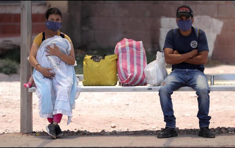 Dos personas esperan en un paradero de autobuses en Tegucigalpa. EFE/G. Amador