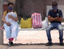 Dos personas esperan en un paradero de autobuses en Tegucigalpa. EFE/G. Amador
