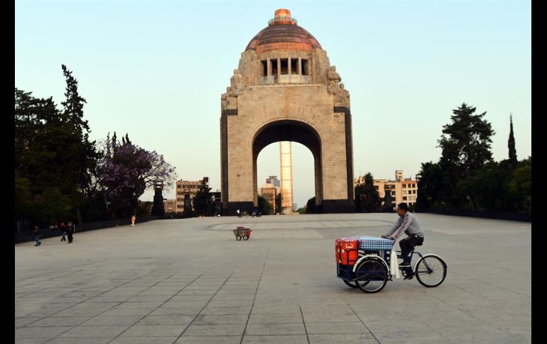 Un vendedor ambulante pasa por el Monumento a la Revolución en la capital del país. EFE/J. Núñez