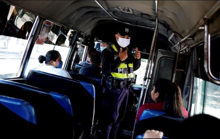 Un agente policial inspecciona que el trasporte público cumpla con normas de seguridad sanitaria en San Salvador. EFE/R. Sura