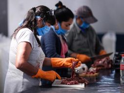 Mujeres cortan carne en la localidad Rafael Castillo en Buenos Aires, donde elementos del Ejército repartieron tres mil raciones de alimentos. EFE/J. Roncoroni