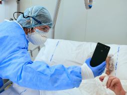 Personal médico ayuda a un enfermo de COVID-19 a llamar a familiares por videoconferencia desde el hospital Papa Giovanni XXIII en Bérgamo, Italia. AFP/P. Cruciatti