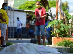 Personas miran un cadáver afuera de una clínica en Guayaquil. AFP/M. Pin