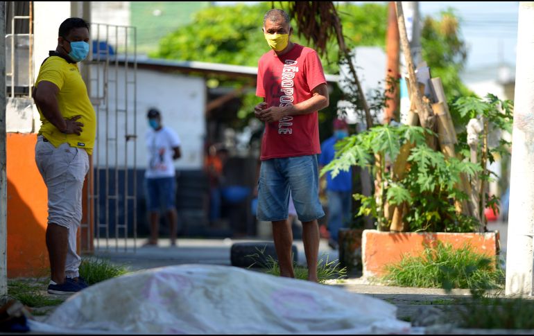Personas miran un cadáver afuera de una clínica en Guayaquil. AFP/M. Pin