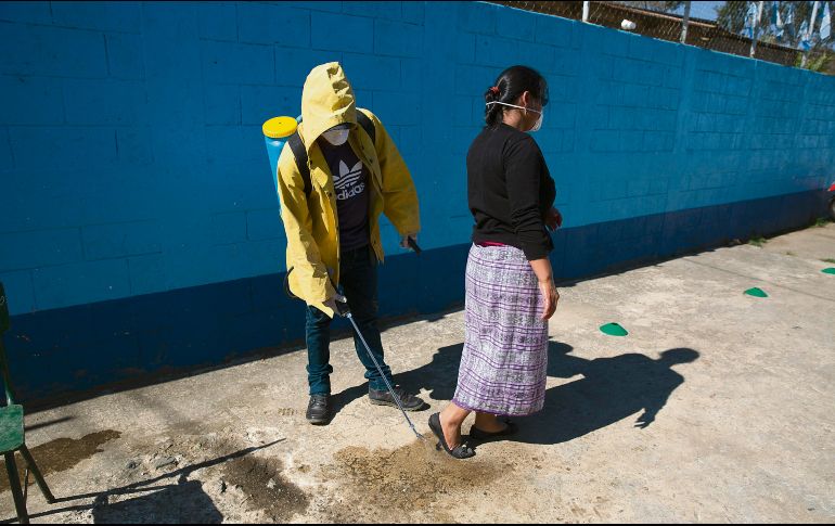 Medidas. Un trabajador aplica desinfectante a una mujer antes de entrar a una escuela en San Martín. AP