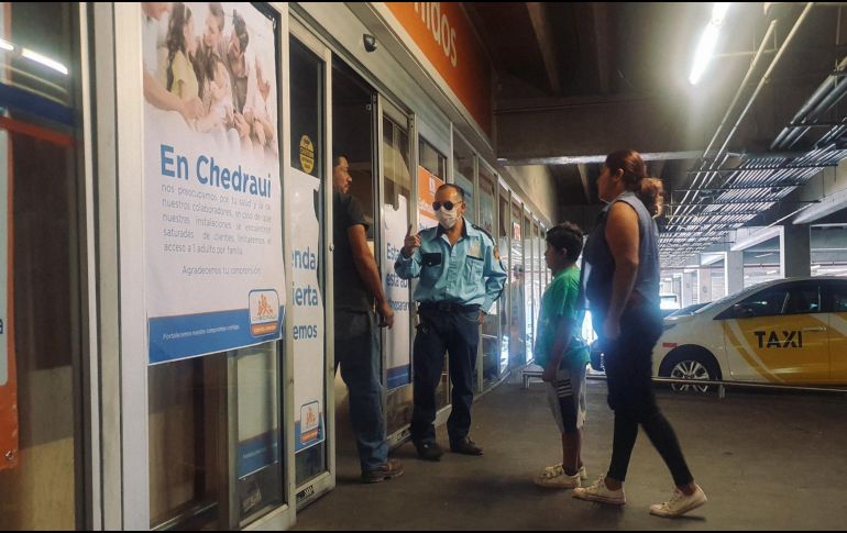 Un oficial a la entrada de una tienda Chedraui exhorta a que ingrese sólo un cliente por familia. EL INFORMADOR / G. Gallo