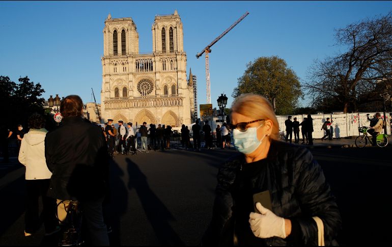 Parisinos alrededor de la catedral mientras repica la campana para recordar el aniversario del incendio y como un aplauso para los trabajadores de la salud que combaten el avance del coronavirus. AP/C. Ena