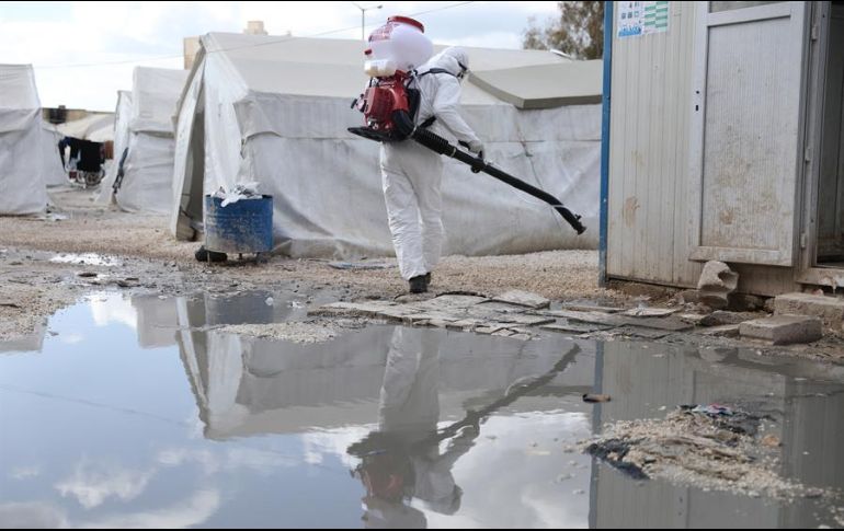 Un voluntario protegido con un traje especial desinfecta un campo de refugiados en Idleb. EFE/Y. Nemah