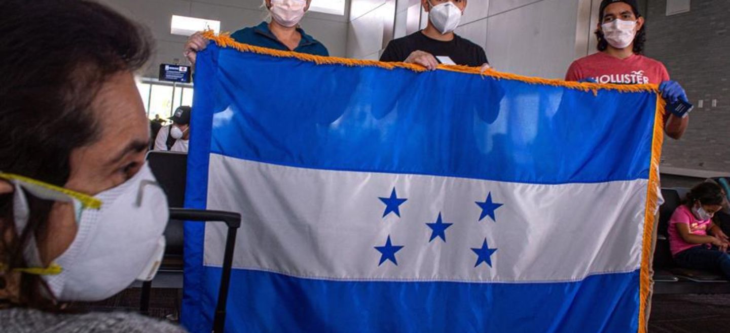 Un grupo de hondureños varados en Estados Unidos por el coronavirus sostienen la bandera nacional ante de subir a un avión este sábado en el Aeropuerto Internacional de Fort Lauderdale. EFE/G. Viera