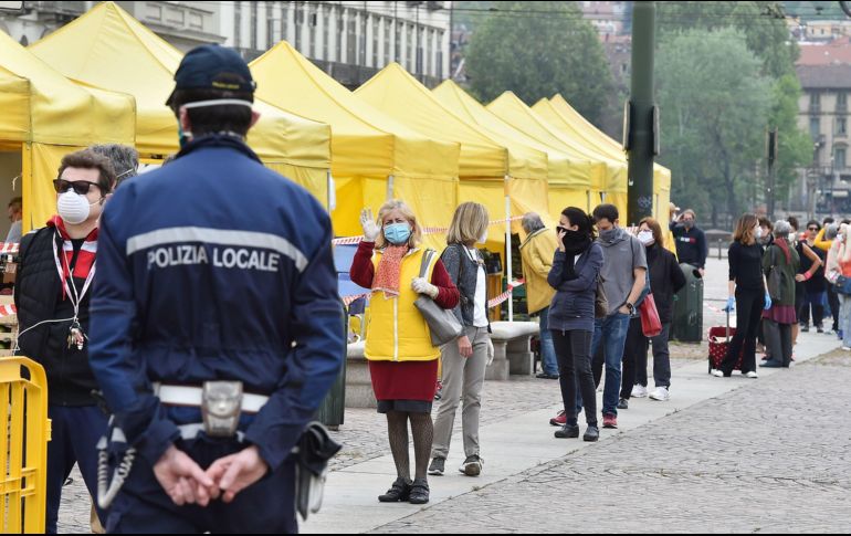 Un policía vigila este domingo mientras personas acuden a un mercado abierto en Turín, Italia. EFE/A. Di Marco