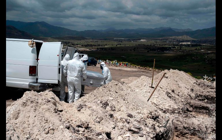 Trabajadores con trajes especiales protectores entierran a una persona fallecida por COVID-19 en el Panteón Municipal número 13 de Tijuana, Baja California. AFP/G. Arias