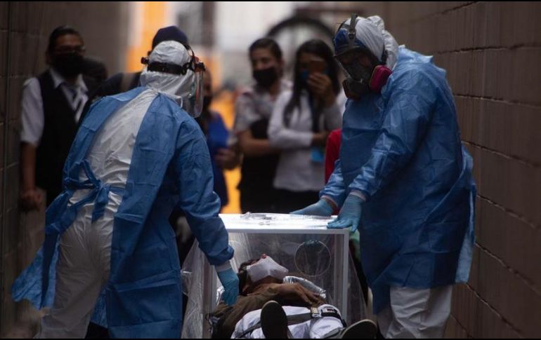 Un hombre de 20 años que se desmayó es conducido con todas las medidas de bioseguridad a una ambulancia a las afueras de un centro comercial en Morelia, Michoacán. EFE/ Iván Villanueva