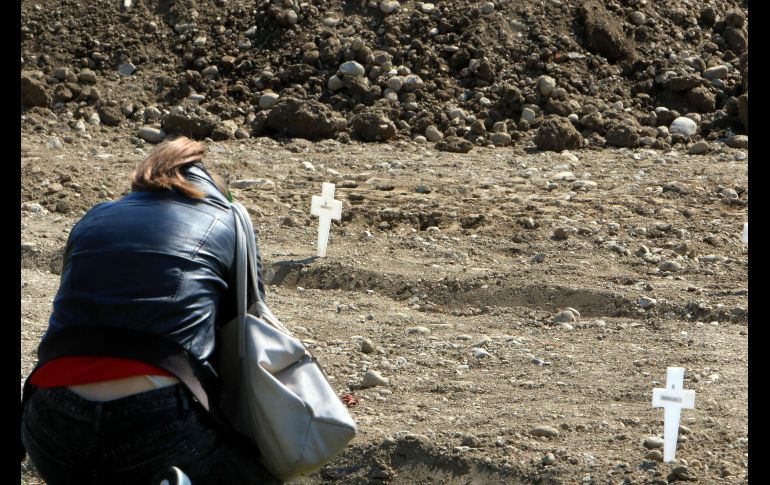 Una mujer ora donde fue sepultado un familiar. Muchas familias no han podido reclamar el cuerpo debido a las drásticas medidas de confinamiento o por la propia condición médica. EFE/EPA/P. Salmoirago