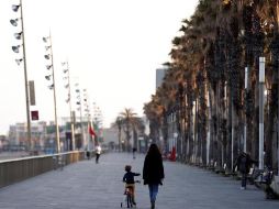 Un menor acompañado pasea con su bicicleta por el paseo marítimo de Barcelona este sábado. EFE/A. García
