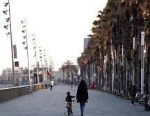 Un menor acompañado pasea con su bicicleta por el paseo marítimo de Barcelona este sábado. EFE/A. García