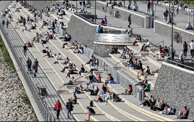 Personas toman hoy el Sol frente al río en Colonia, Alemania. Autoridades piden no bajar la guardia, pero las normas de distanciamiento social se han ido relajando en la práctica. AP/M. Meissner