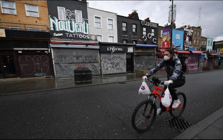 Una persona a bordo de una bicicleta carga comida para entregar a domicilio, en un barrio de Inglaterra. EFE/A. Rain