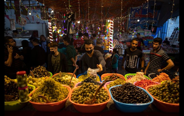 Un vendedor palestino usa un cubrebocas  mientras vende encurtidos en un mercado de la Ciudad de Gaza durante el Ramadán. AP/K. Hamra