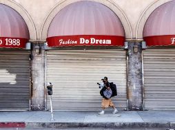 Un hombre protegido por un cubrebocas camina frente a una tienda cerrada en Los Ángeles, California. EFE/E. Laurent
