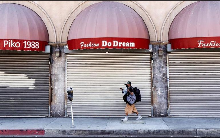 Un hombre protegido por un cubrebocas camina frente a una tienda cerrada en Los Ángeles, California. EFE/E. Laurent