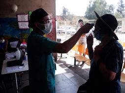 Un enfermero toma la temperatura a una mujer antes de su ingreso a un centro de salud en la comuna de Pedro Aguirre Cerda en Santiago,Chile. EFE/A. Valdés