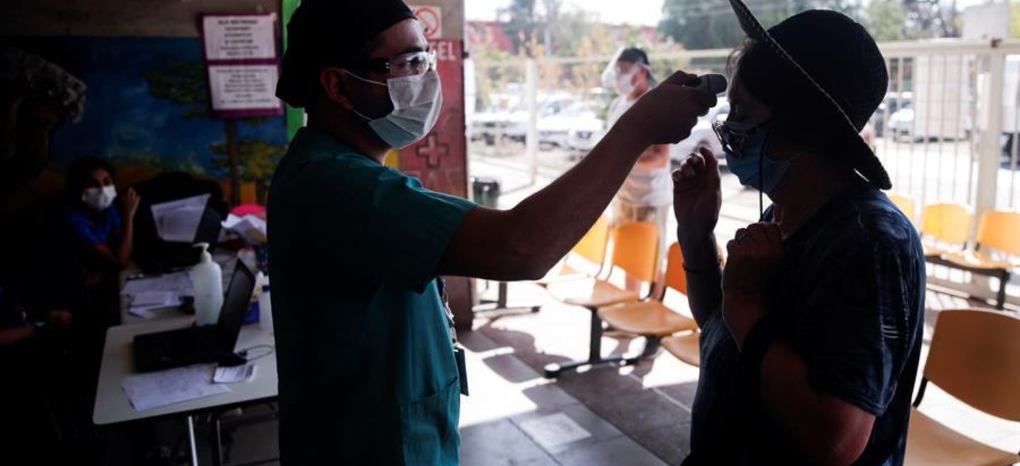 Un enfermero toma la temperatura a una mujer antes de su ingreso a un centro de salud en la comuna de Pedro Aguirre Cerda en Santiago,Chile. EFE/A. Valdés