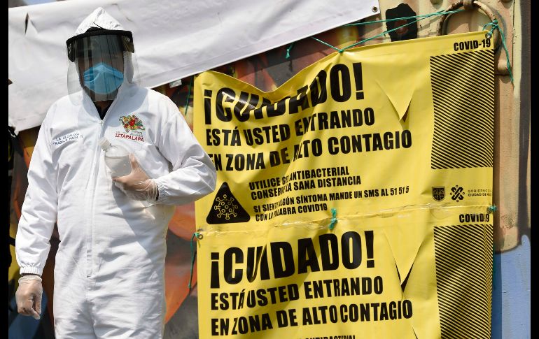 Un trabajador de la alcaldía de Iztapalapa da gel antibacterial a quienes ingresan al panteón. AFP/A. Estrella