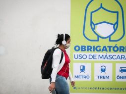 Una joven camina frente a un letrero que indica que el uso de la máscara es obligatorio en el transporte público este miércoles, en Sao Paulo. EFE/ F. Bizerra