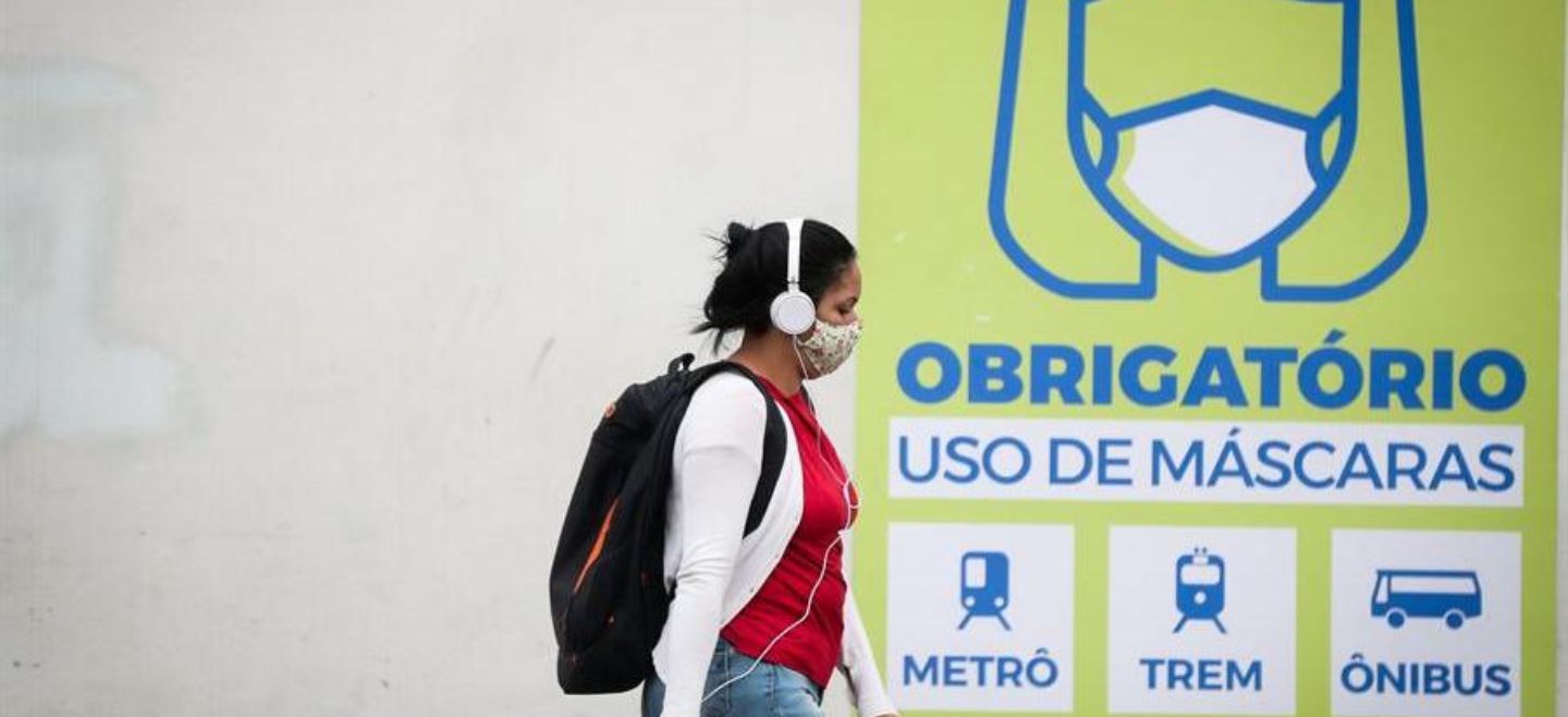 Una joven camina frente a un letrero que indica que el uso de la máscara es obligatorio en el transporte público este miércoles, en Sao Paulo. EFE/ F. Bizerra