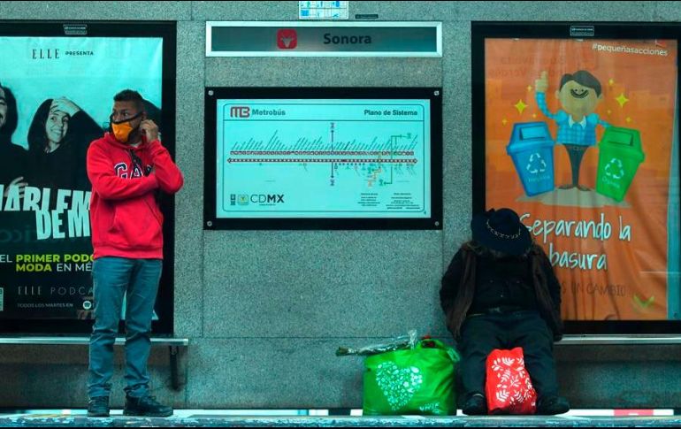 Dos personas esperan su transporte en una estación de Metrobús, en la Ciudad de México. EFE/J. Núñez
