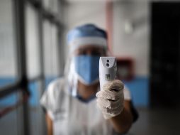 Una enfermera con tapabocas y protector toma la temperatura este jueves a quienes ingresan al Hospital El Cruce, en la localidad de Florencio Varela, en Buenos Aires. EFE/J. Roncoroni