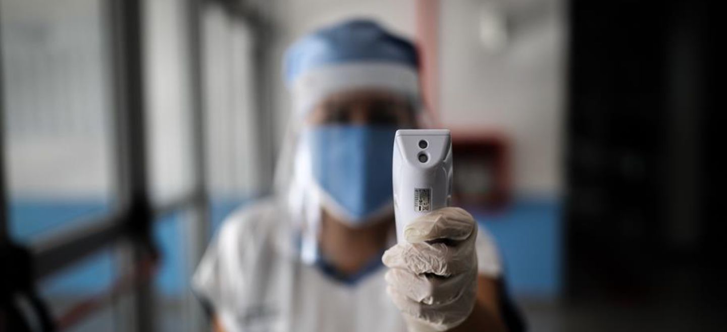 Una enfermera con tapabocas y protector toma la temperatura este jueves a quienes ingresan al Hospital El Cruce, en la localidad de Florencio Varela, en Buenos Aires. EFE/J. Roncoroni
