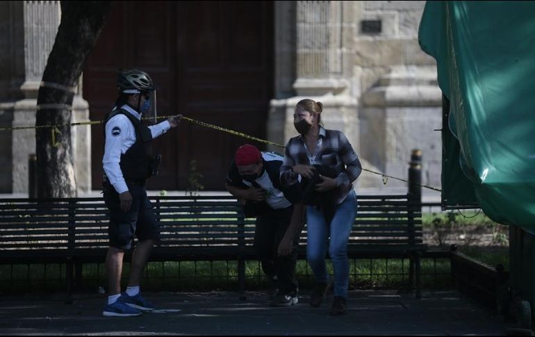 Aún no. Policías instan a unas personas a no sentarse en una banca bloqueada por una cinta amarilla. EL INFORMADOR/F. Atilano