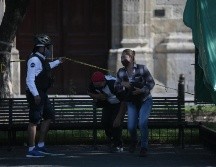 Aún no. Policías instan a unas personas a no sentarse en una banca bloqueada por una cinta amarilla. EL INFORMADOR/F. Atilano