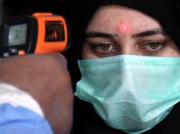 Un trabajador de una estación de tren mide la temperatura de una pasajera en Karachi, Pakistán, este miércoles. EFE/R. Khan