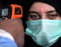 Un trabajador de una estación de tren mide la temperatura de una pasajera en Karachi, Pakistán, este miércoles. EFE/R. Khan