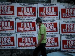 Un hombre camina junto a varios carteles de protesta que piden la salida del presidente Jair Bolsonaro, en Sao Paulo. EFE/F. Bizerra