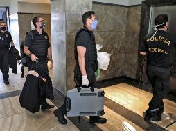 Policías federales cargan con lo que podría ser evidencia contra Wilson Witzel. AFP/F. Motta