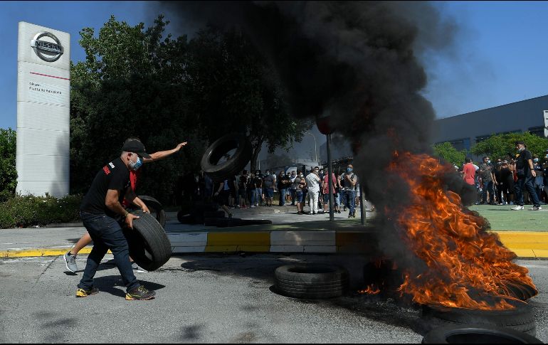 Cientos de trabajadores se concentran este jueves ante la planta y han empezado a quemar neumáticos como protesta por la decisión de la compañía automotriz. AFP/Ll. Gene